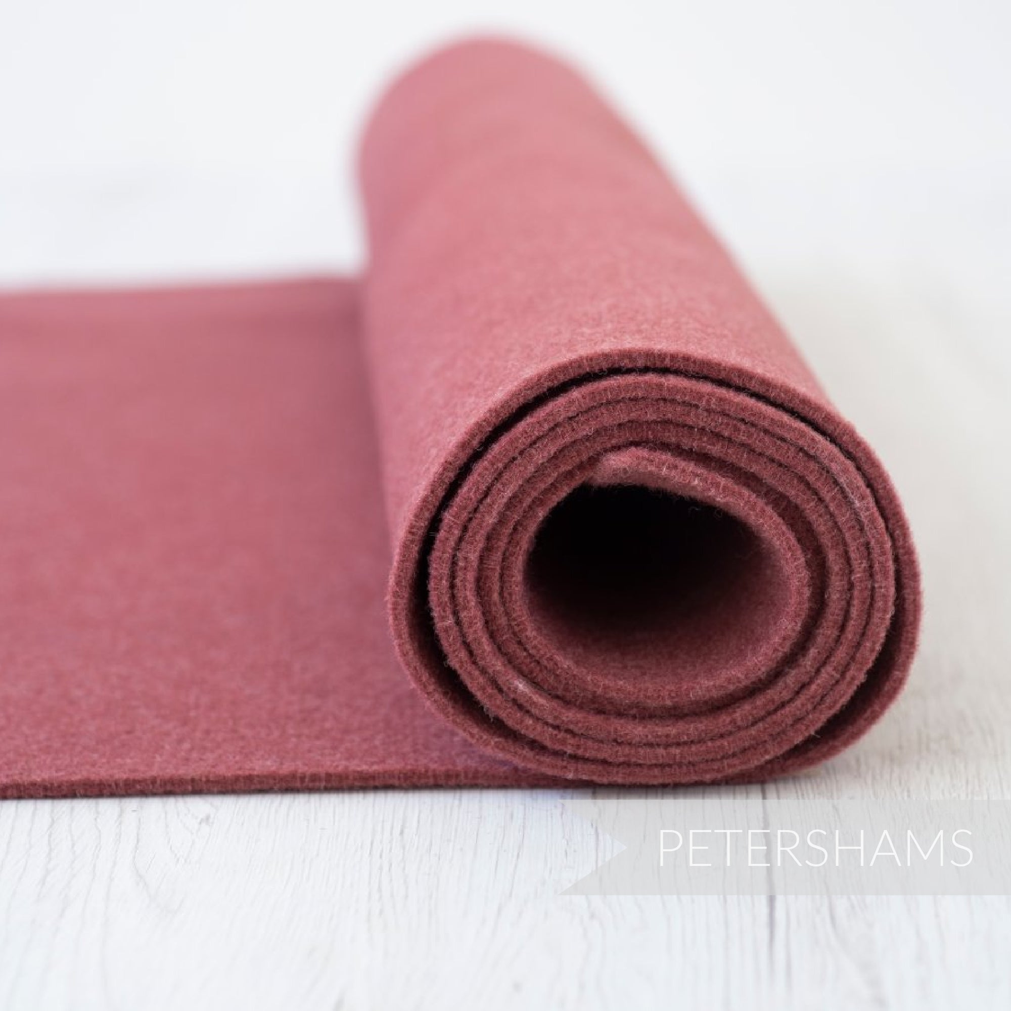 Petershams Millinery Supplies 3mm thick thermoformable wool felt fabric in a dusty rose colour rolled on a white surface