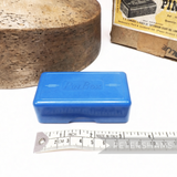 Petershams Millinery Supplies vintage blue Bakelite pin box with embossed lid text, shown next to a measuring tape.