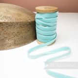 Petershams Millinery Supplies 10mm vintage light blue velvet ribbon on a wooden spool next to a wooden hat block