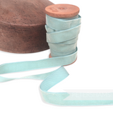 Petershams Millinery Supplies vintage light blue velvet ribbon on a wooden spool next to a wooden millinery block.