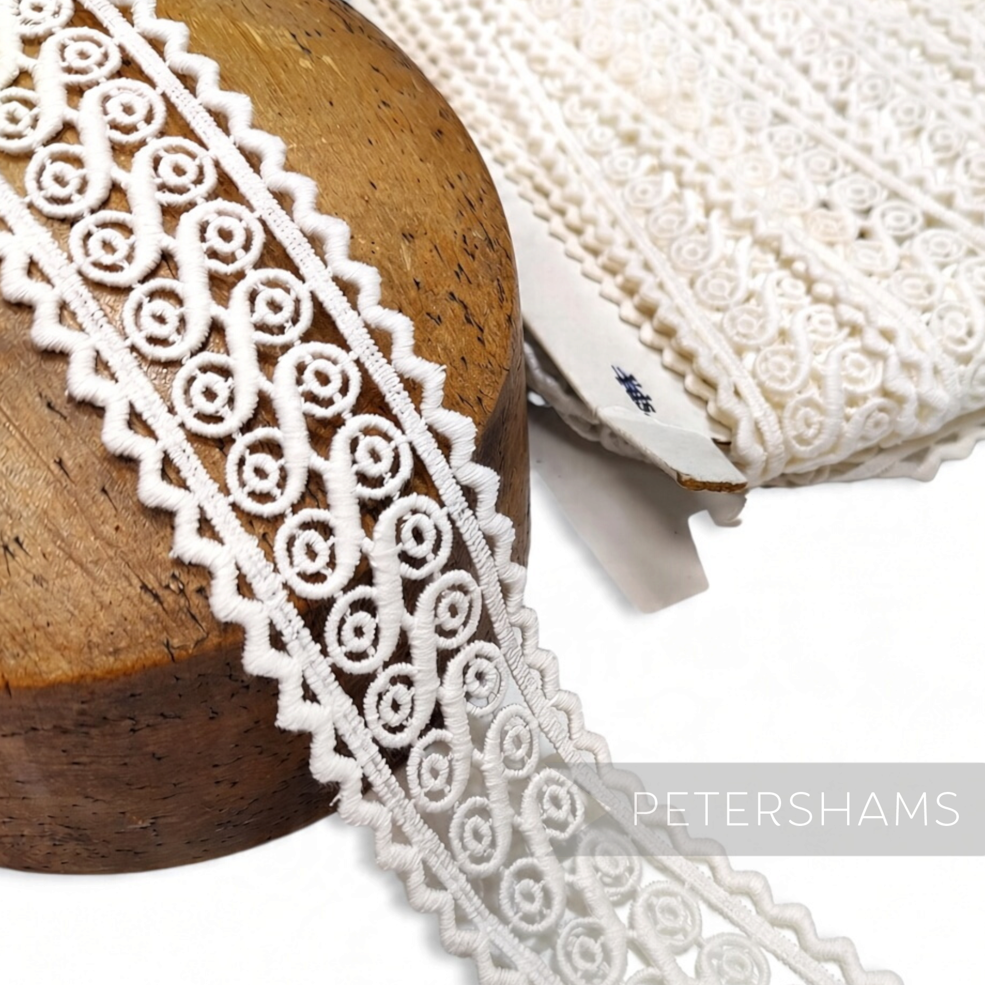 Petershams Millinery Supplies vintage off-white 100% cotton guipure lace trim with a swirly pattern and zaggy edge.