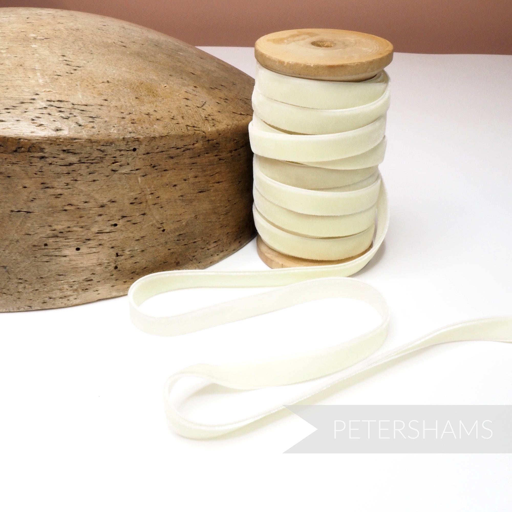Petershams Millinery Supplies 10mm vintage cream velvet ribbon on a wooden spool next to a wooden hat block