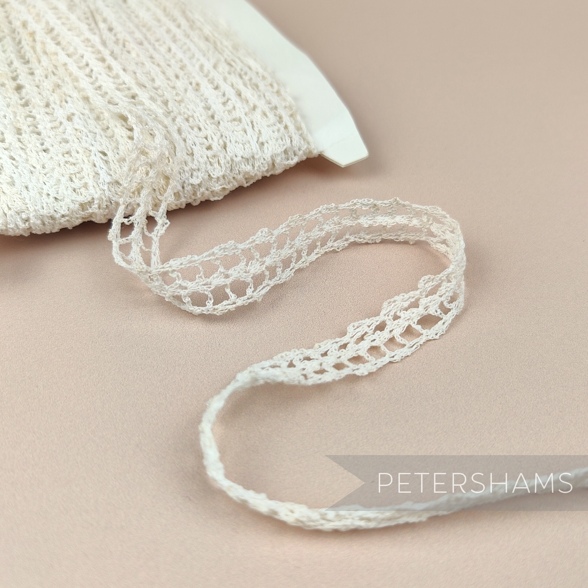 Petershams Millinery Supplies vintage 14mm loose knit grid lace trim on a card with light foxing and discolouration.
