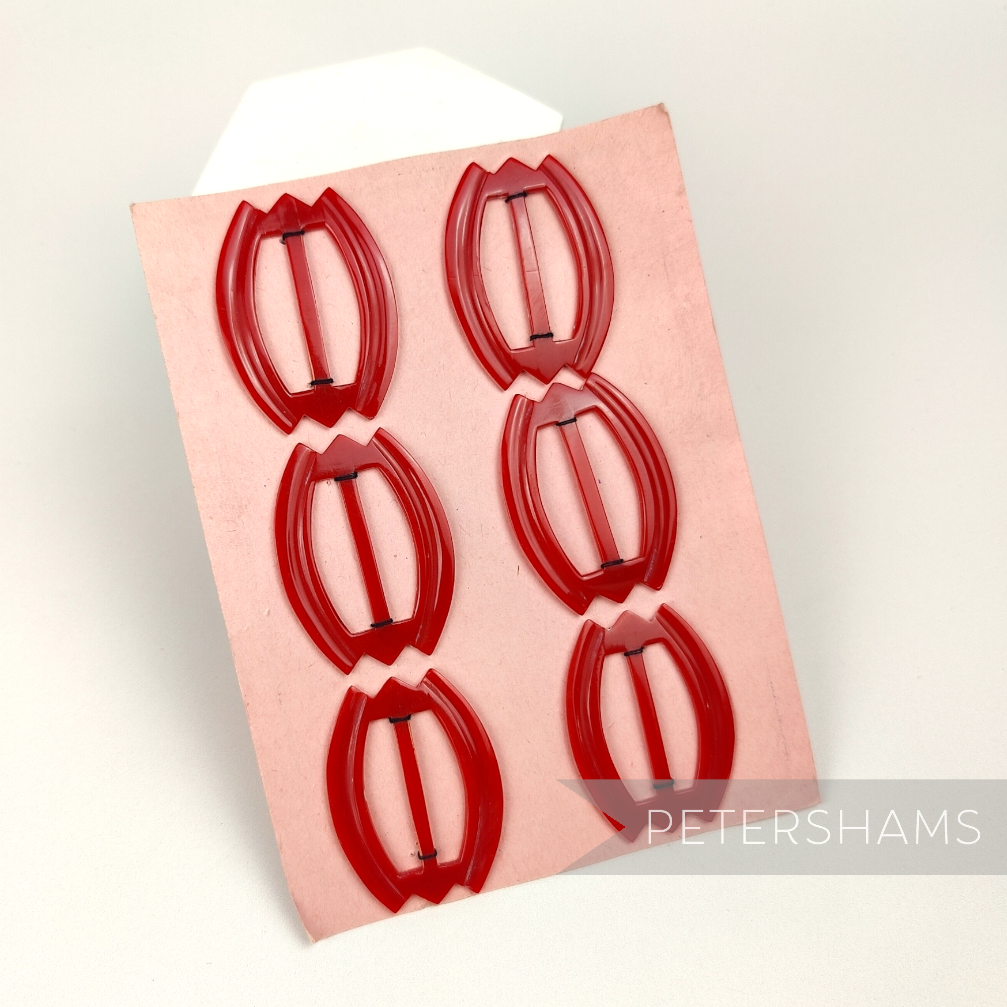 Petershams Millinery Supplies vintage red plastic tulip hat buckles on a display card