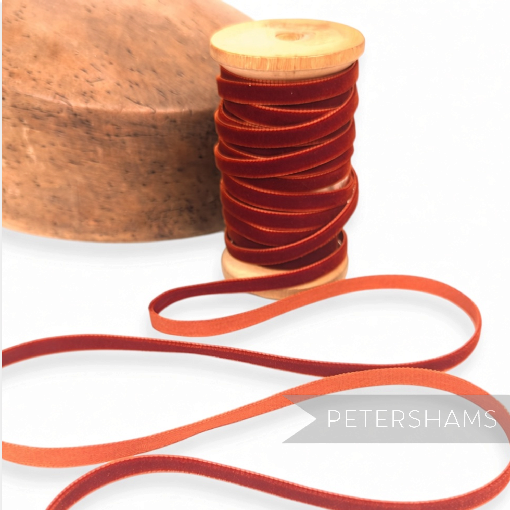 Petershams Millinery Supplies 7mm vintage rust red velvet ribbon on a wooden spool next to a millinery block