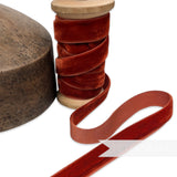 Petershams Millinery Supplies 16mm vintage russet velvet ribbon on a wooden spool next to a wooden millinery block.