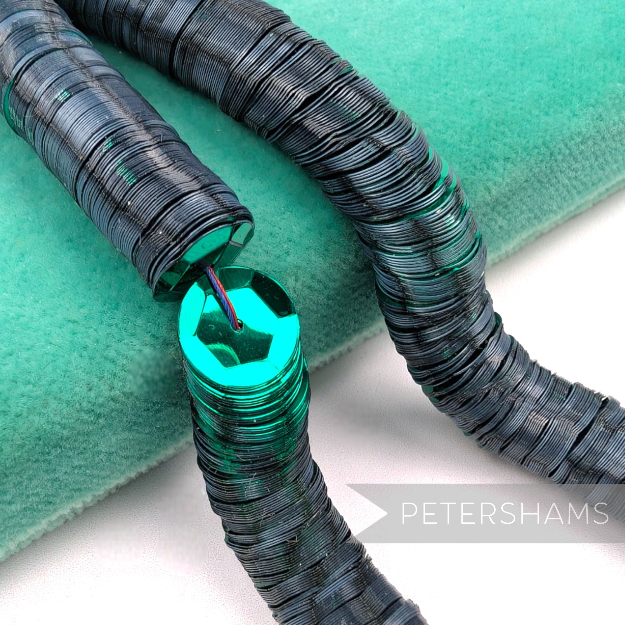 Petershams Millinery Supplies 10mm vintage cupped French sequins in dark metallic green on a green velvet surface
