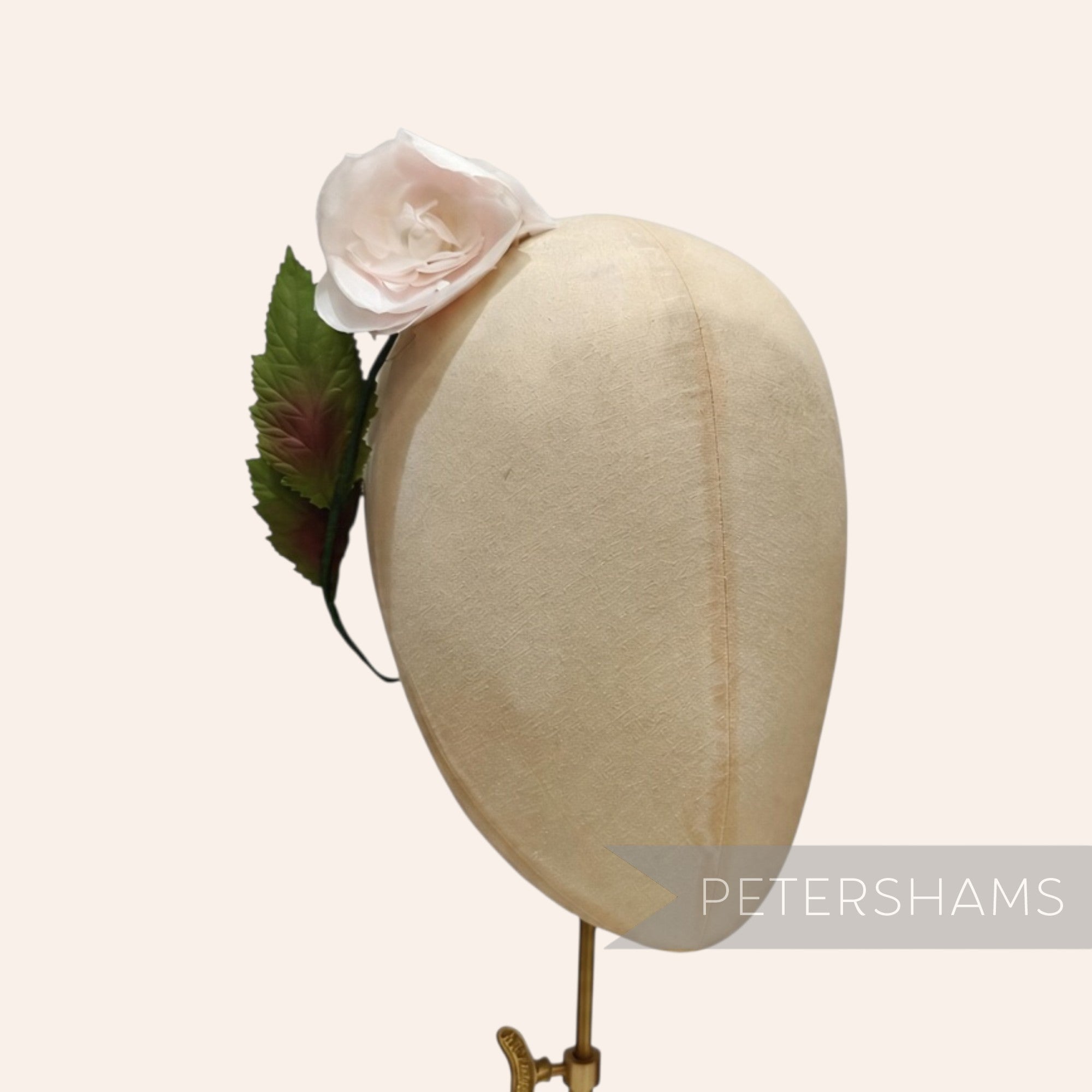 Petershams Millinery Supplies vintage 1960s silk rosebud flower with green wired leaves on a millinery head form