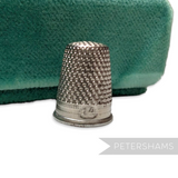 Petershams Millinery Supplies vintage German steel sewing thimble with dimpled texture on a green velvet background