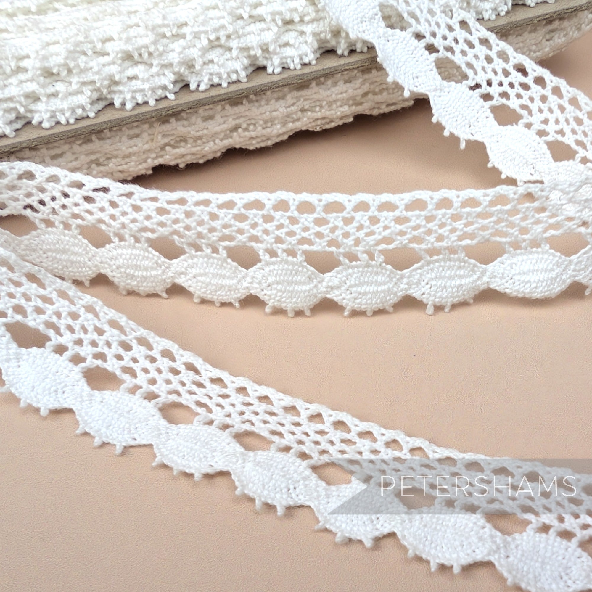 Petershams Millinery Supplies 22mm white cotton eyelash lace trim with an intricate scalloped edge pattern.