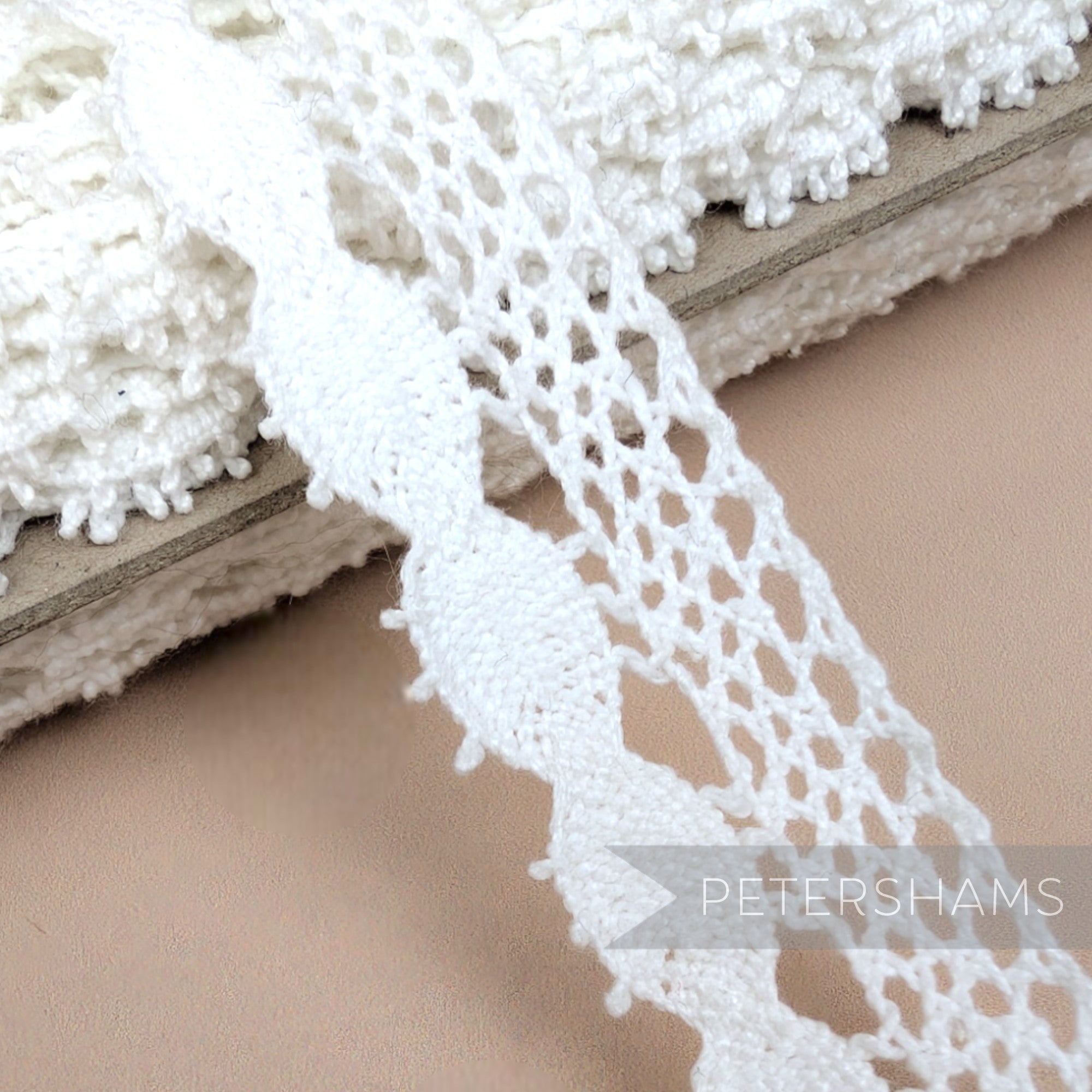 Petershams Millinery Supplies 22mm white cotton eyelash lace trim with an intricate openwork pattern on a spool.