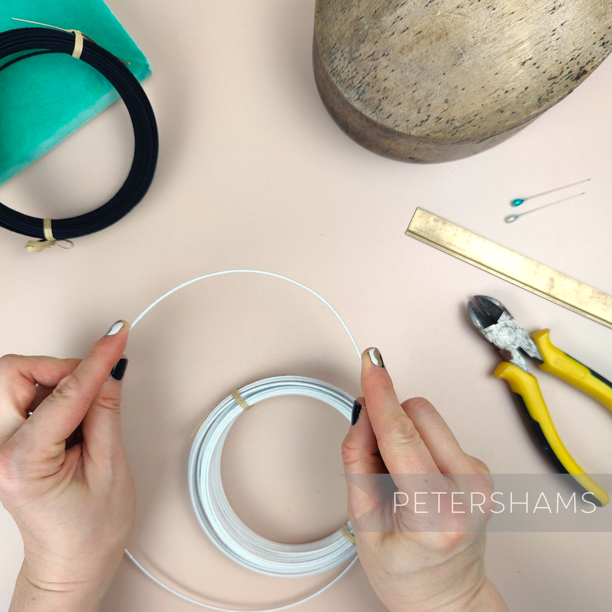 Petershams Millinery Supplies 1.2mm white cotton covered millinery wire held by hands with tools