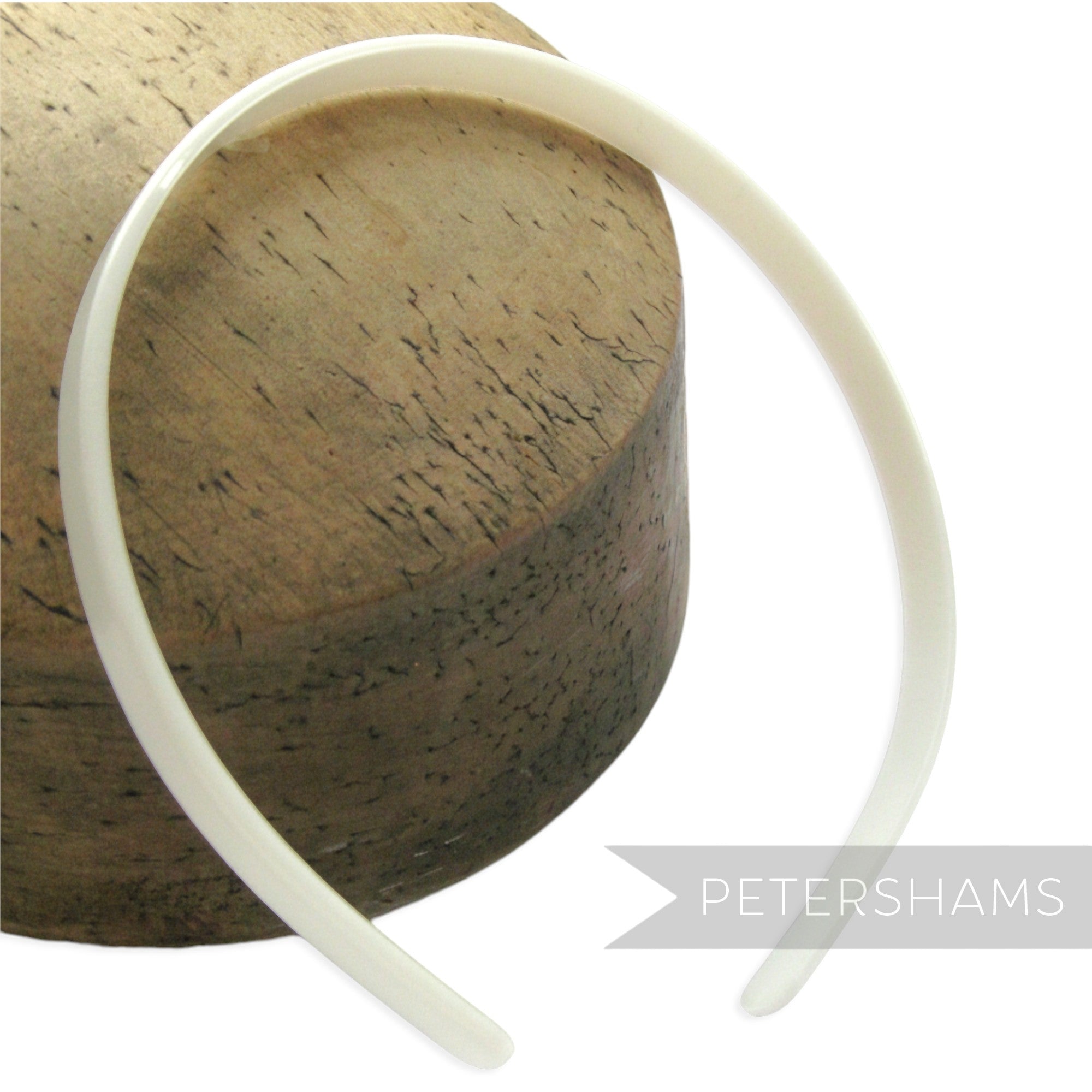 Petershams Millinery Supplies white plastic headband core blank for DIY hair accessory crafting on a wooden block