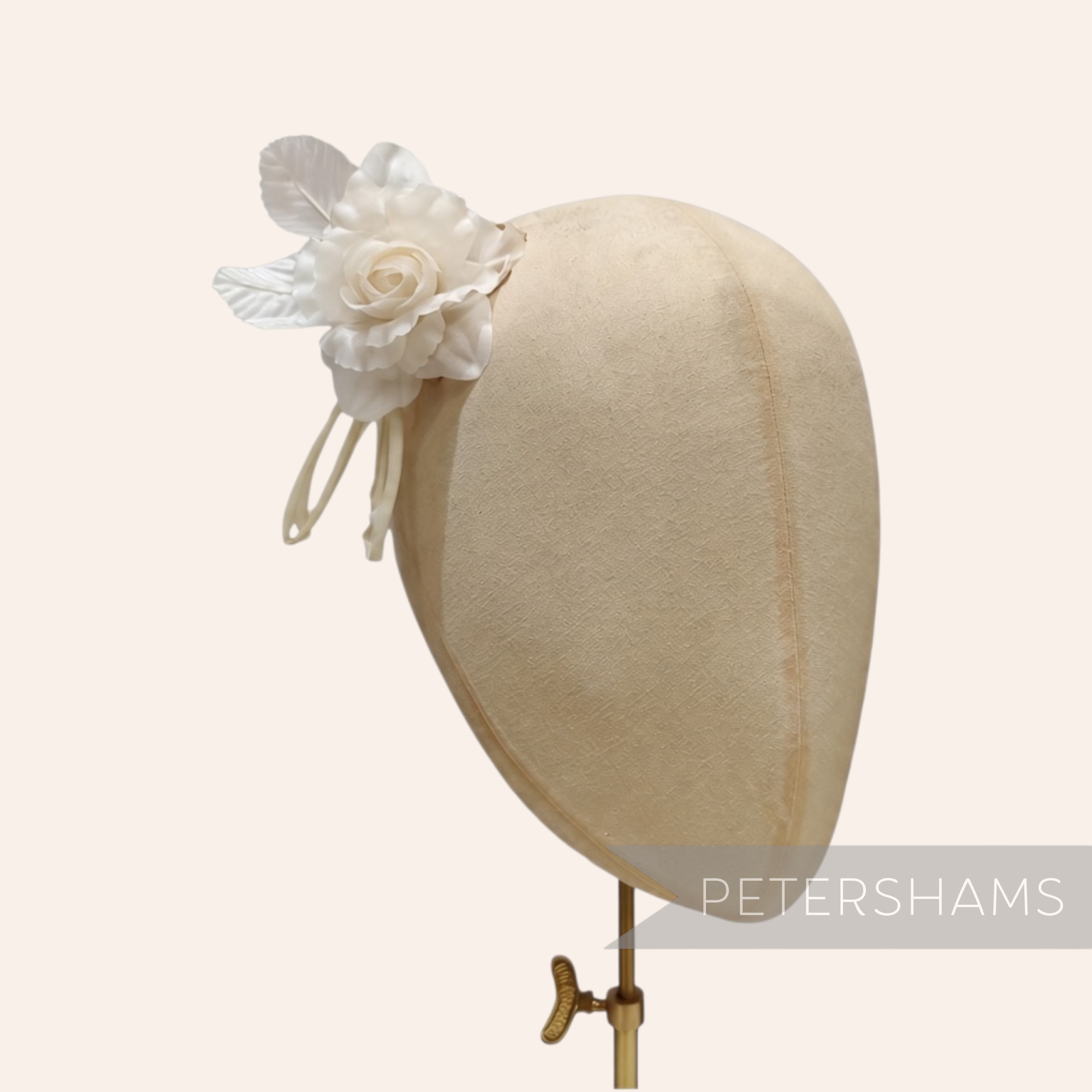 Petershams Millinery Supplies Zahra petite white silk flower hat mount with wired leaves on a millinery head block.