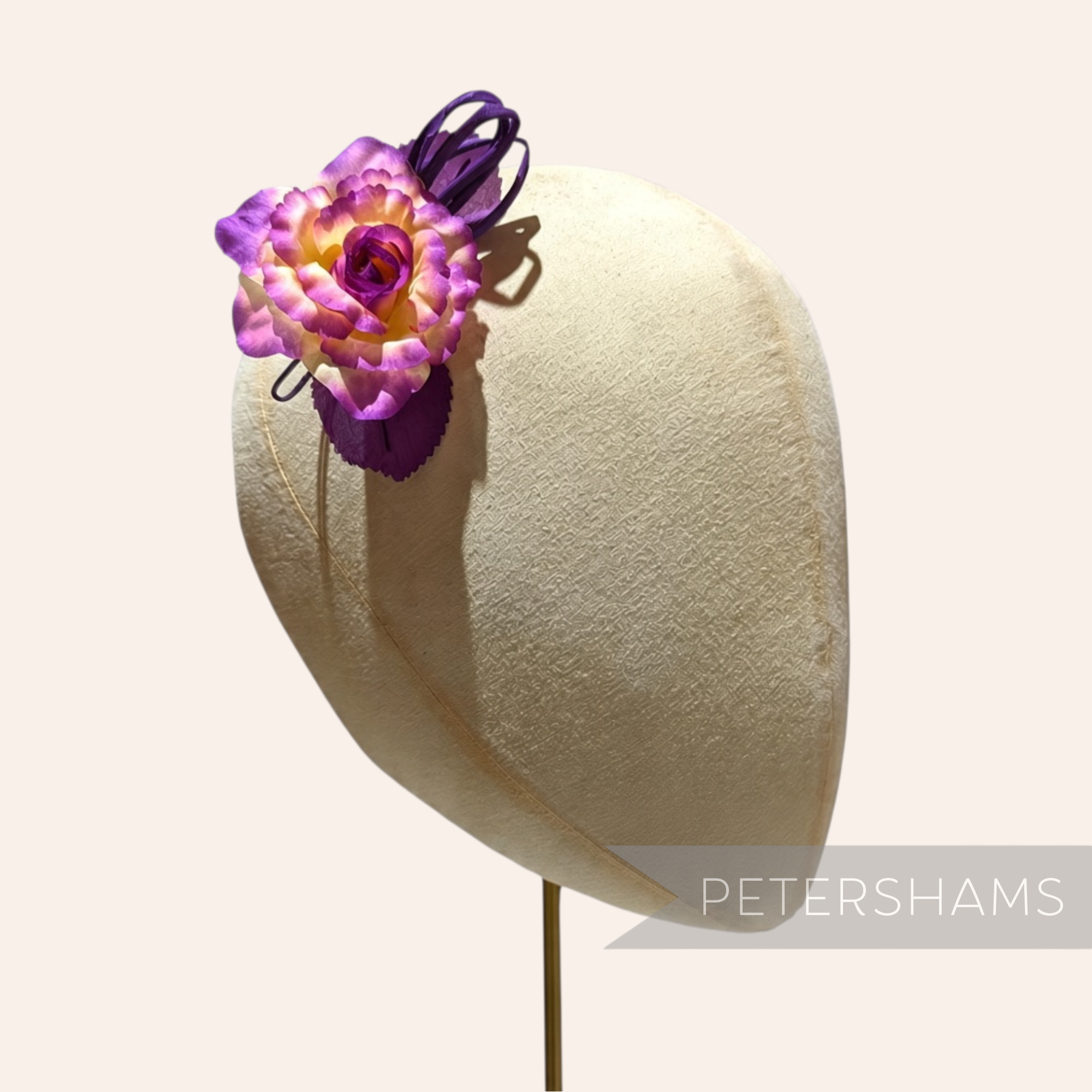 Petershams Millinery Supplies Zahra petite silk flower hat mount in purple and yellow on a millinery head block.