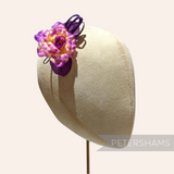 Petershams Millinery Supplies Zahra petite silk flower hat mount in purple and yellow on a millinery head block.